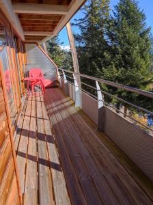 a wooden deck with a red chair on a balcony at Arolles D21 - Chamrousse 1700 - Les Villages du Bachat in Chamrousse