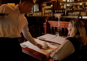 mężczyzna i kobieta siedzący przy stole w restauracji w obiekcie Parkhotel Mastbosch Breda w mieście Breda
