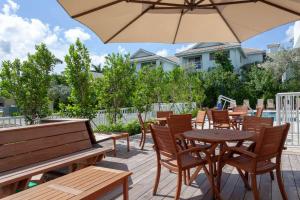 eine Terrasse mit Tischen, Stühlen und einem Sonnenschirm in der Unterkunft Maritime Hotel Fort Lauderdale Airport & Cruiseport in Fort Lauderdale