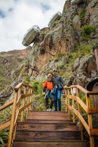 duas pessoas a subir uma escada de madeira numa montanha em Starlodge Adventure Suites em Urubamba