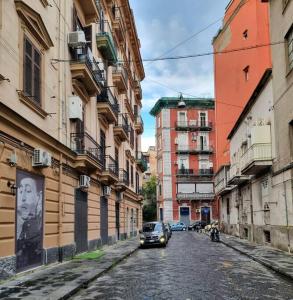um carro a descer uma rua da cidade com edifícios em Casa comoda e centrale in quartiere storico di Napoli em Nápoles