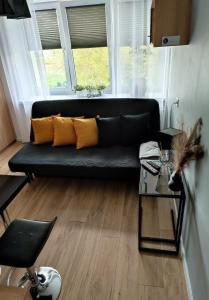 a black couch with yellow pillows in a living room at Apartamenty Urban Concept in Zamość