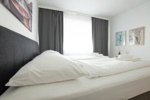 Cama blanca con almohadas blancas y ventana en Charming Apartment with Balcony, Close to Stephansdom Cathedral, en Viena