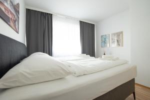 Cette chambre comprend un grand lit blanc et une fenêtre. dans l'établissement Charming Apartment with Balcony, Close to Stephansdom Cathedral, à Vienne