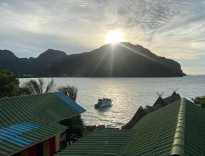 Phi Phi Goodview Bungalow في جزيرة في في: قارب في الماء مع الشمس على جبل