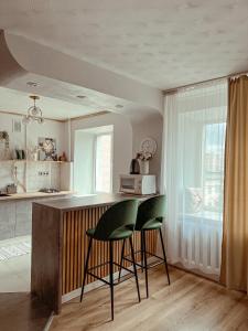 uma cozinha com duas cadeiras verdes e um balcão em Уютная студия в скандинавском стиле в центре em Astana