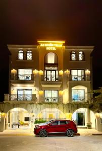 a red car parked in front of a building at An Nhiên Villa Hotel in Phú Mỹ