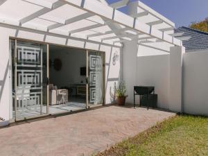 une pergola blanche attachée à une maison avec une terrasse dans l'établissement McLeod's & Stuart's Cottage, à Somerset West