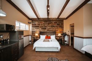 a bedroom with a bed and a stone wall at Rockdell Lodge in Stutterheim