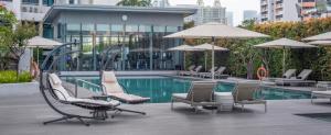 Fraser Suites Singapore في سنغافورة: مسبح وكراسي ومظلات بجانب مبنى