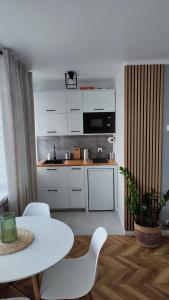 a kitchen with white cabinets and a table and chairs at Apartamenty Urban Concept in Zamość