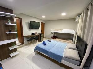 Dormitorio con cama y escritorio con monitor en The Férias | Suites Luxo, en Cabo Frío