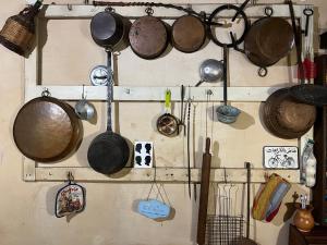 a bunch of pots and pans hanging on a wall at La Preta Nera in Giuliano di Roma