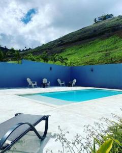 einen Pool mit Stühlen und einer blauen Wand in der Unterkunft Bel appartement en loma au calme in Las Terrenas