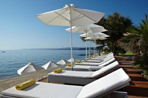 a row of white chairs and umbrellas on a beach at Villa Sophia Afitos in Afitos