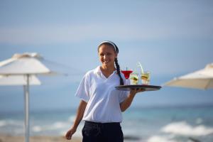 a woman holding a tray of drinks on the beach at Villa Sophia Afitos in Afitos