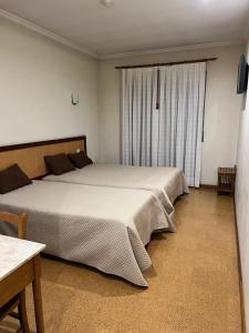 1 dormitorio con 2 camas y ventana en Ze da Rampa Hotel, en Aves