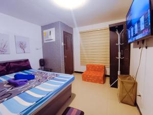 Schlafzimmer mit einem Bett, einem TV und einem Stuhl in der Unterkunft UNO'S Place with Karaoke,Wifi,Netflix and Balcony in Anabu Primero