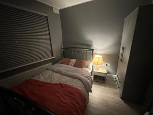 a bedroom with a bed and a lamp and a window at Herbies Stay in Southend-on-Sea