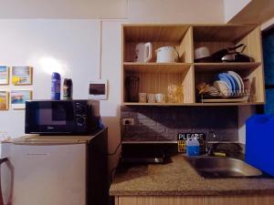eine Küche mit einer Spüle, einer Mikrowelle und einem Kühlschrank in der Unterkunft UNO'S Place with Karaoke,Wifi,Netflix and Balcony in Anabu Primero
