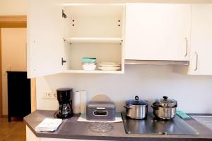 a kitchen with white cabinets and a counter with pots and pans at Cozy Apartment in Eppelheim in Eppelheim