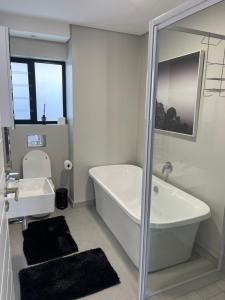 a white bathroom with a tub and a sink at Flat 4 Block 12 Bellamare in Port Elizabeth +13 photos