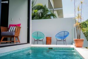 a house with a swimming pool and two chairs at Tropical Loft Home - Ocean View in San Juan del Sur