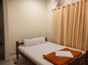 Una cama con sábanas blancas y toallas marrones. en Misty Coorg Homestay, en Kushālnagar