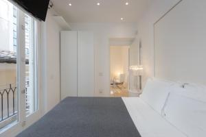 a white bedroom with a bed and a large window at Amazing Cozy Piazza Venezia in Rome