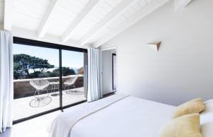 a white bedroom with a bed and a balcony at The Beach House in Olmeto +16 photos