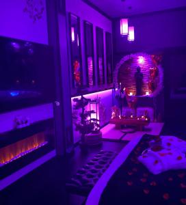 een woonkamer met paarse verlichting en een open haard bij Loveroom romantique et insolite avec jacuzzi proche de Toulouse 