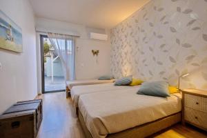 a bedroom with two beds and a wall with a window at Villa Thalassa Stavromenos beach in Magnisía