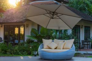 einen Stuhl mit Kissen und einen Regenschirm vor einem Haus in der Unterkunft Le Baan Thai Boutique Villa in Chiang Mai