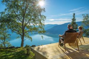 a man and a woman sitting on a deck overlooking a lake at Sørheim FjordPanorama in Skjolden