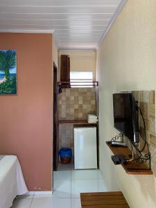 uma cozinha com um frigorífico e uma televisão num quarto em Pousada Sitio Araça em São Miguel dos Milagres