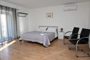 a white bedroom with a bed and two chairs at Sweet Home in Capua