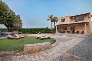 a house with a patio and a yard with chairs and grass at Villa Thalassa Stavromenos beach in Magnisía