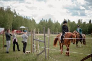 a woman is riding a horse while people stand around at Heidin Mummola Farm in Pello