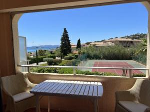 un banc assis sur un balcon avec un court de tennis dans l'établissement L'Appartement des Sables, au Lavandou