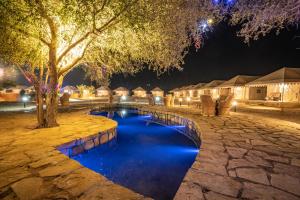 a resort pool at night with trees and huts at Tripli Hotels Stay Inn Resort Jaisalmer in Sām