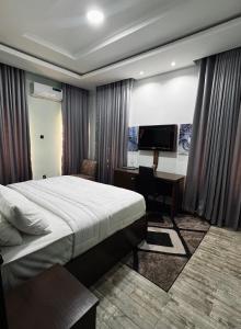 伊巴丹Fragrance Apartments and Suites的一间卧室，配有一张床、一张书桌和一台电视