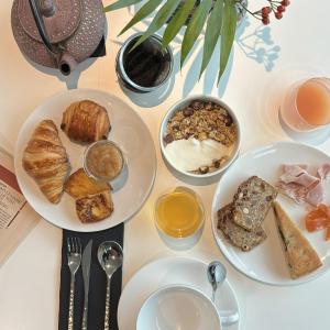 a table topped with plates of food and bowls of bread at L'Agapa Hôtel - Spa Codage in Perros-Guirec