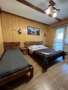 a bedroom with two beds in a room with wooden walls at Zarichna Lyks in Slavske