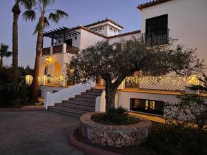 ein weißes Haus mit einem Baum davor in der Unterkunft Luxe Haciënda La Campiña met verwarmd zwembad en tennisbaan. in Alhaurín el Grande