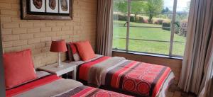 2 camas en una habitación con ventana en Daneswold Country Cottage, en Hogsback