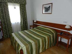 1 dormitorio con cama, mesa y ventana en Albergaria Senhora do Espinheiro, en Seia