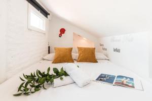 Un dormitorio blanco con una cama con un libro. en Charming La Latina Home, en Madrid