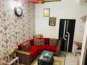 a living room with a red couch and a clock on the wall at Udaipur Stays 2 in Udaipur