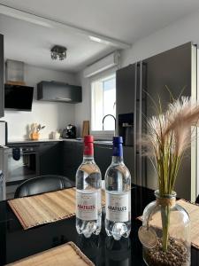 two bottles of wine sitting on a table in a kitchen at Le Balcon de Léo - Proche centre & Parc des expos in Bordeaux