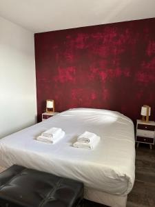 a bedroom with a white bed with a red wall at Le Balcon de Léo - Proche centre & Parc des expos in Bordeaux